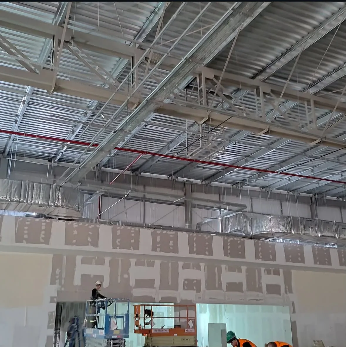 Obra comercial com paredes de drywall e instalações aparentes no teto